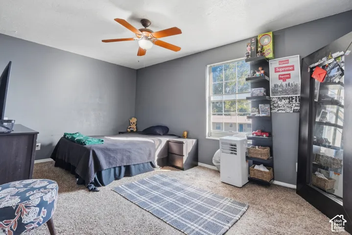 Carpeted flooring, ceiling fan, window with natural light, built-in shelving, and a mirrored closet door