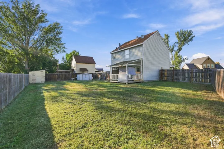 Expansive backyard featuring a covered porch, wood fencing, and mature trees