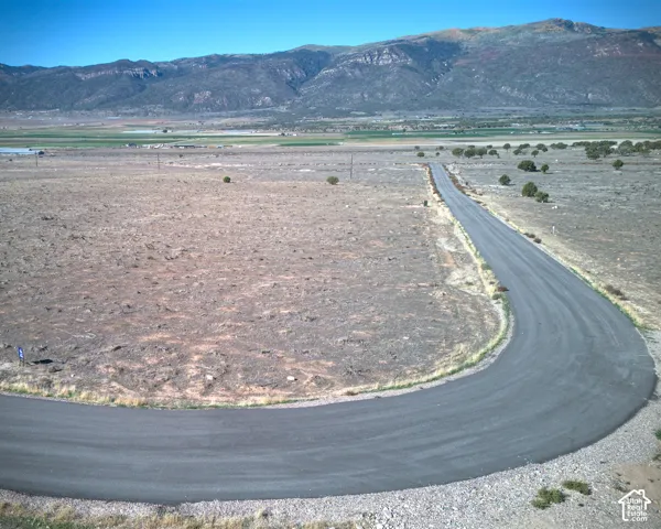 Paved access road extending through the property, surrounded by open land and distant mountains