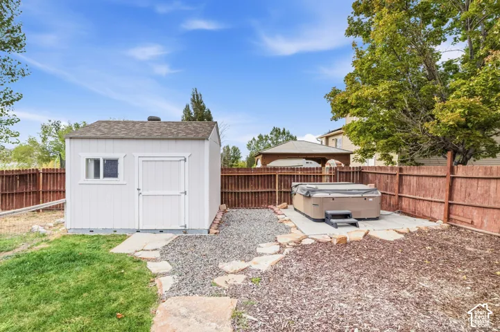 Backyard featuring a privacy fence, storage shed, and hot tub on a concrete pad