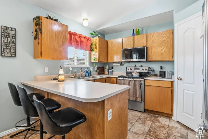 Kitchen featuring wood-finish cabinetry, stainless steel microwave, stainless steel range, and light-toned countertops