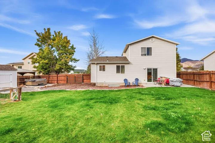 Expansive grassy yard with a concrete patio, wood privacy fence, and a storage shed
