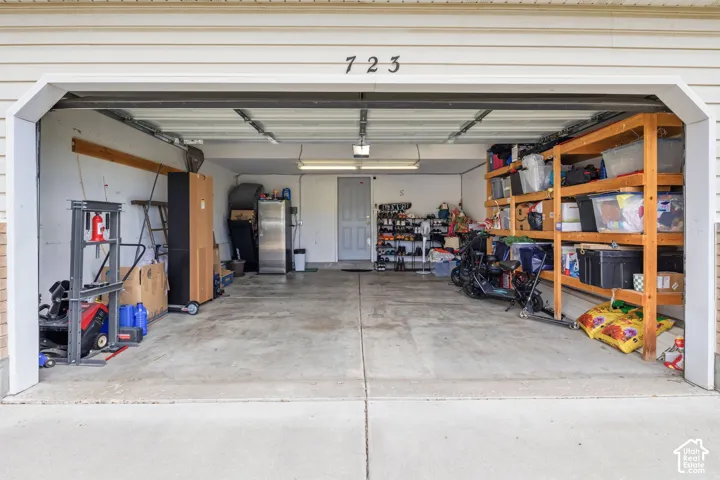 Attached garage with a concrete floor, overhead lighting, and white paneled walls