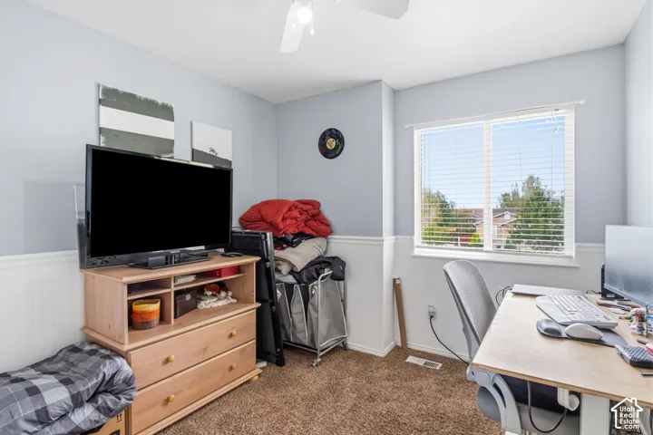 Window with horizontal blinds, light blue wall paint, white wainscoting, and brown carpet flooring
