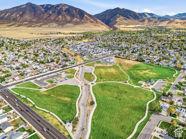 Expansive green spaces featuring walking paths, integrated playground structures, and mountain backdrops