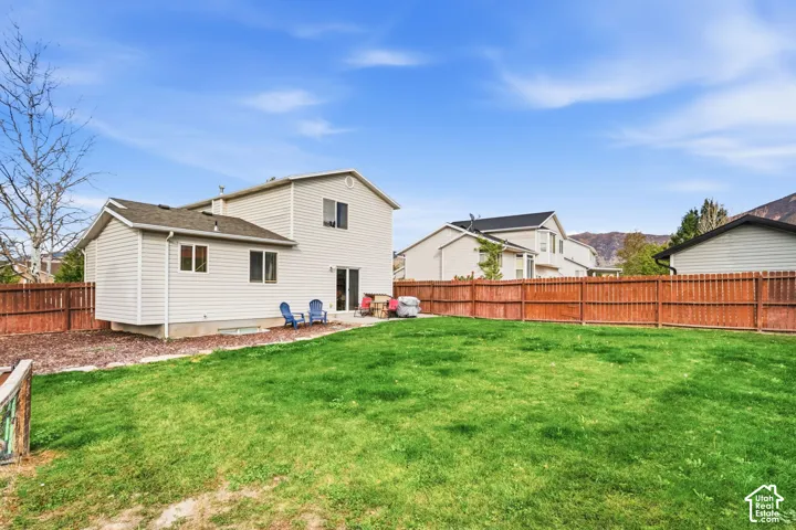 Expansive lawn area with a perimeter wood fence, light-colored siding, and a dark shingle roof