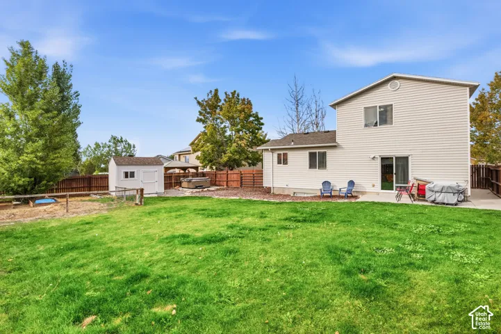 Expansive grassy yard with a white storage shed and a privacy fence