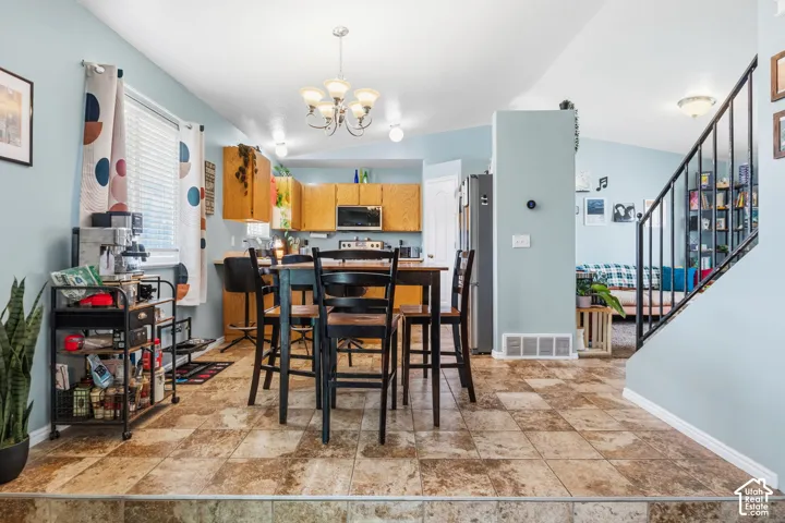 Kitchen with light wood-finish cabinetry, black appliances, and a breakfast bar