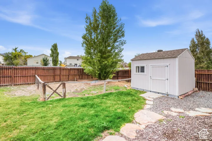 Enclosed backyard featuring a privacy fence, a storage shed, a stone pathway, and a grass area