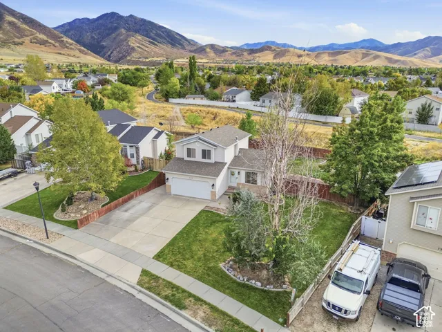 Two-story residence with an attached garage, concrete driveway, and front lawn