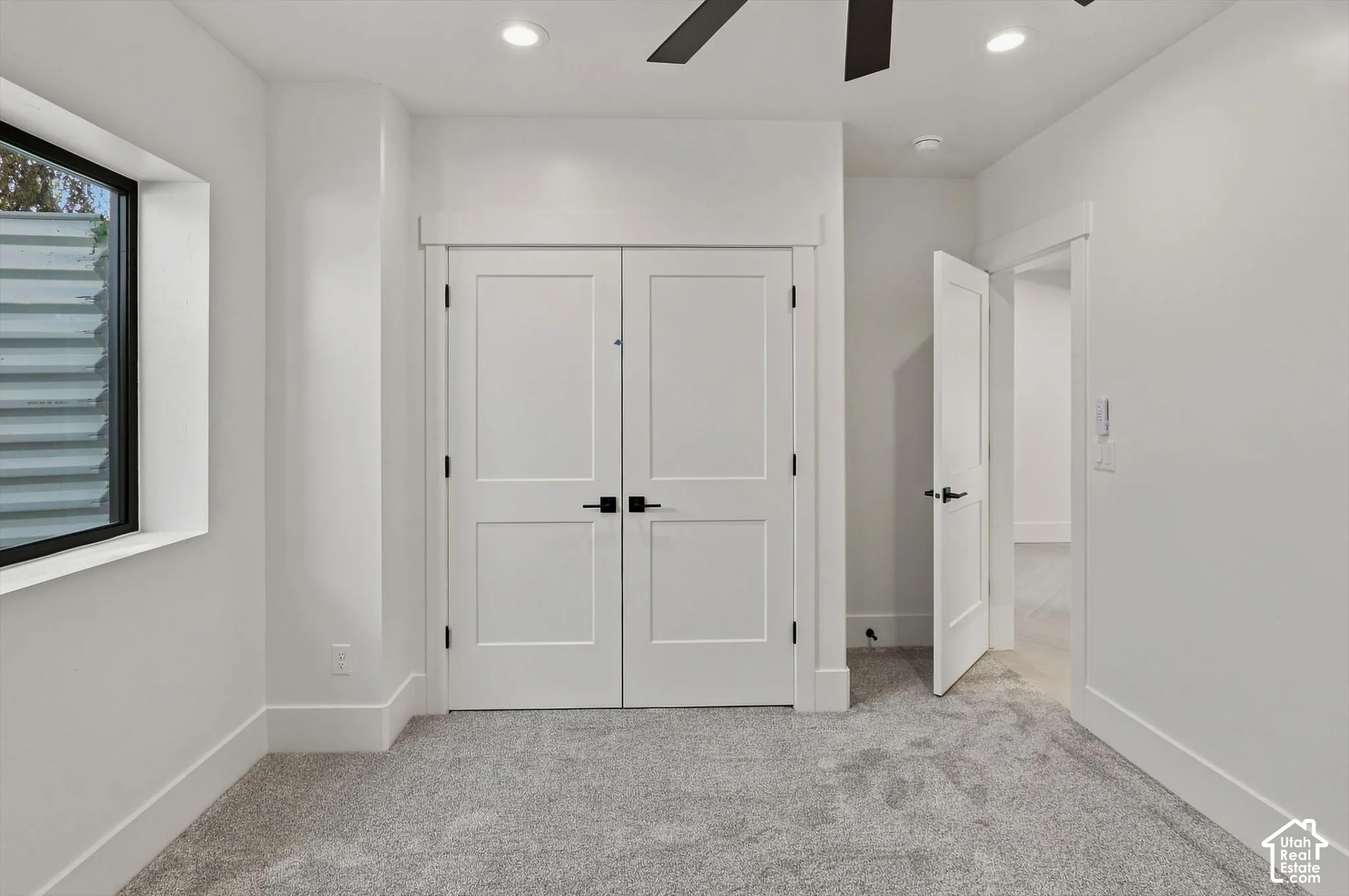 Plush gray carpeting, white painted walls, recessed lighting, and a modern ceiling fan