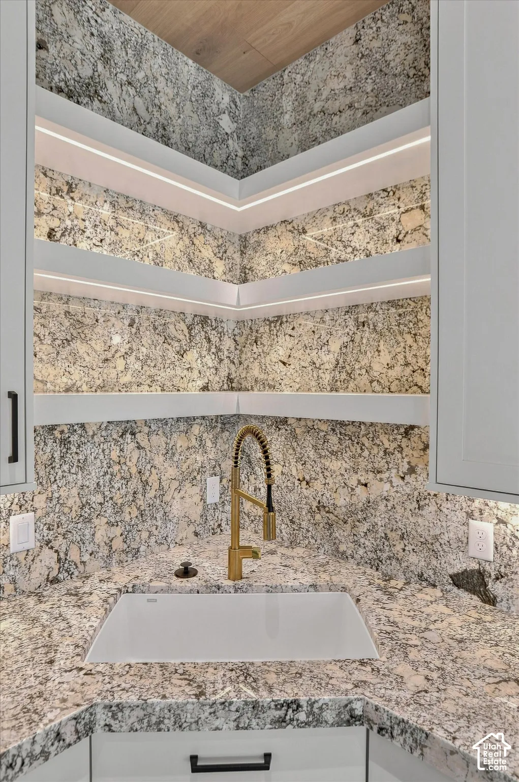 Granite countertops and backsplash complement the integrated sink and gold-finish gooseneck faucet