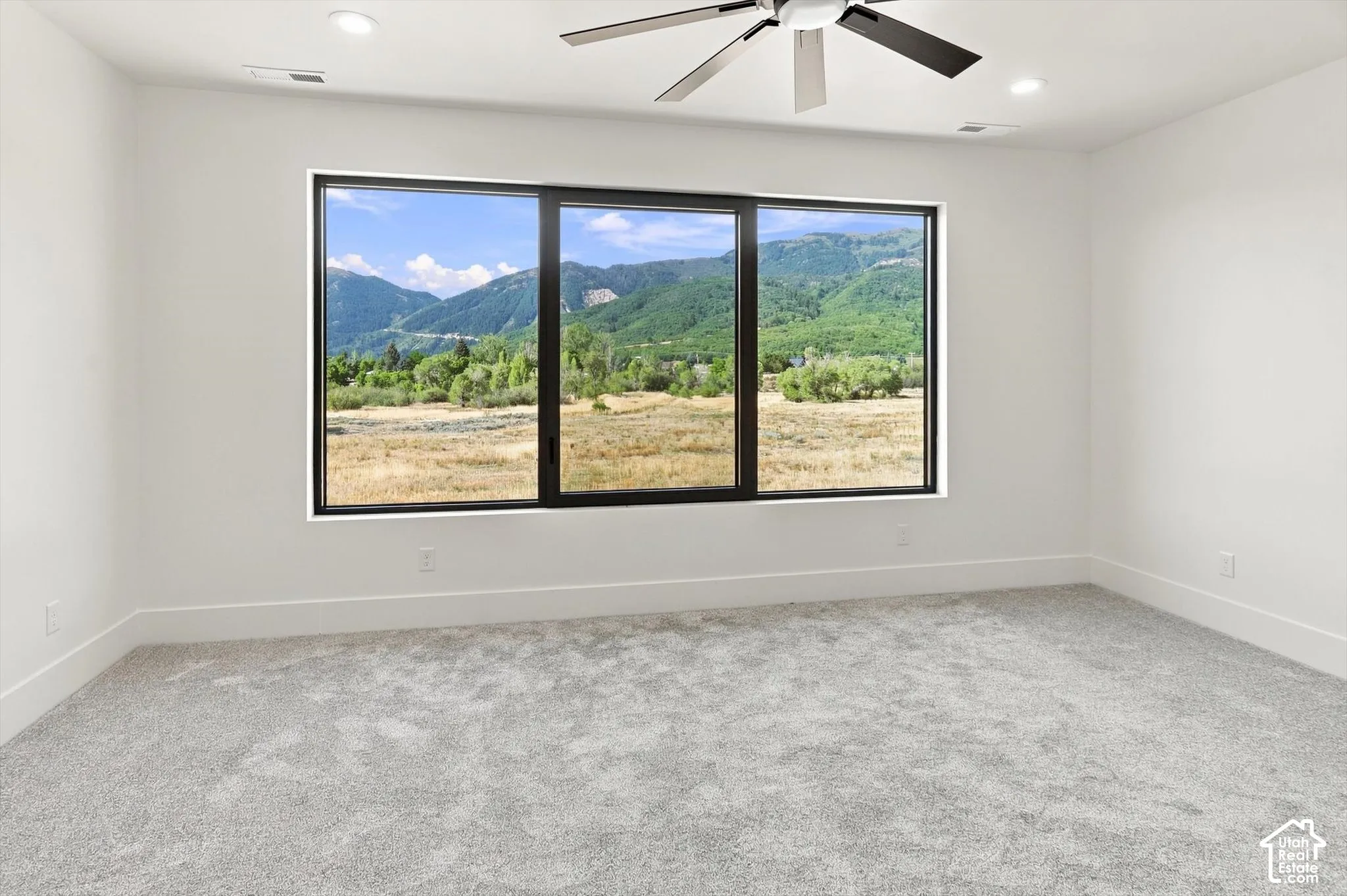 Expansive window offering mountain scenery, recessed ceiling lighting, ceiling fan, and carpeted flooring