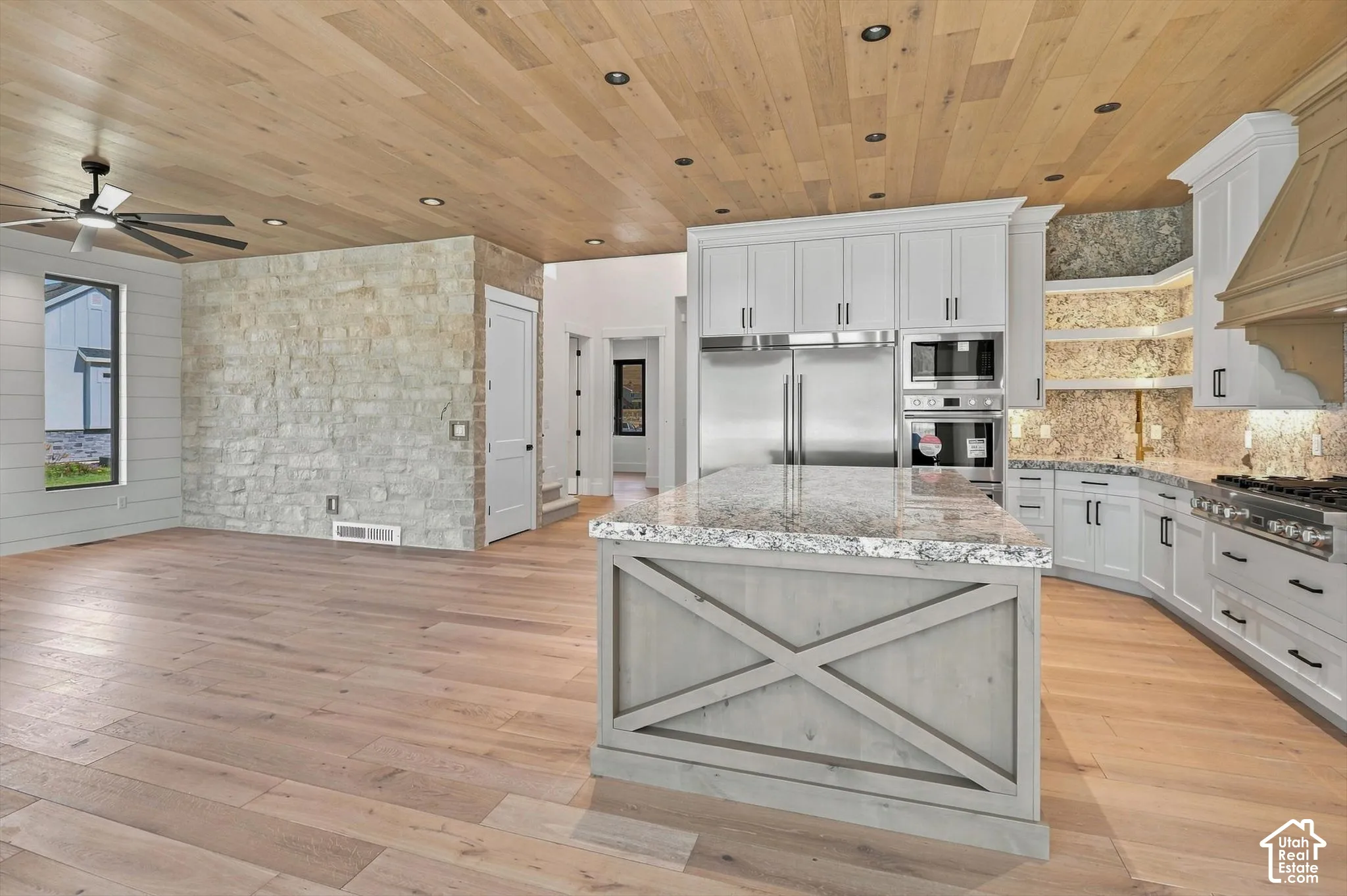 Gourmet kitchen with stainless steel appliances, granite countertops, and light wood-finish flooring