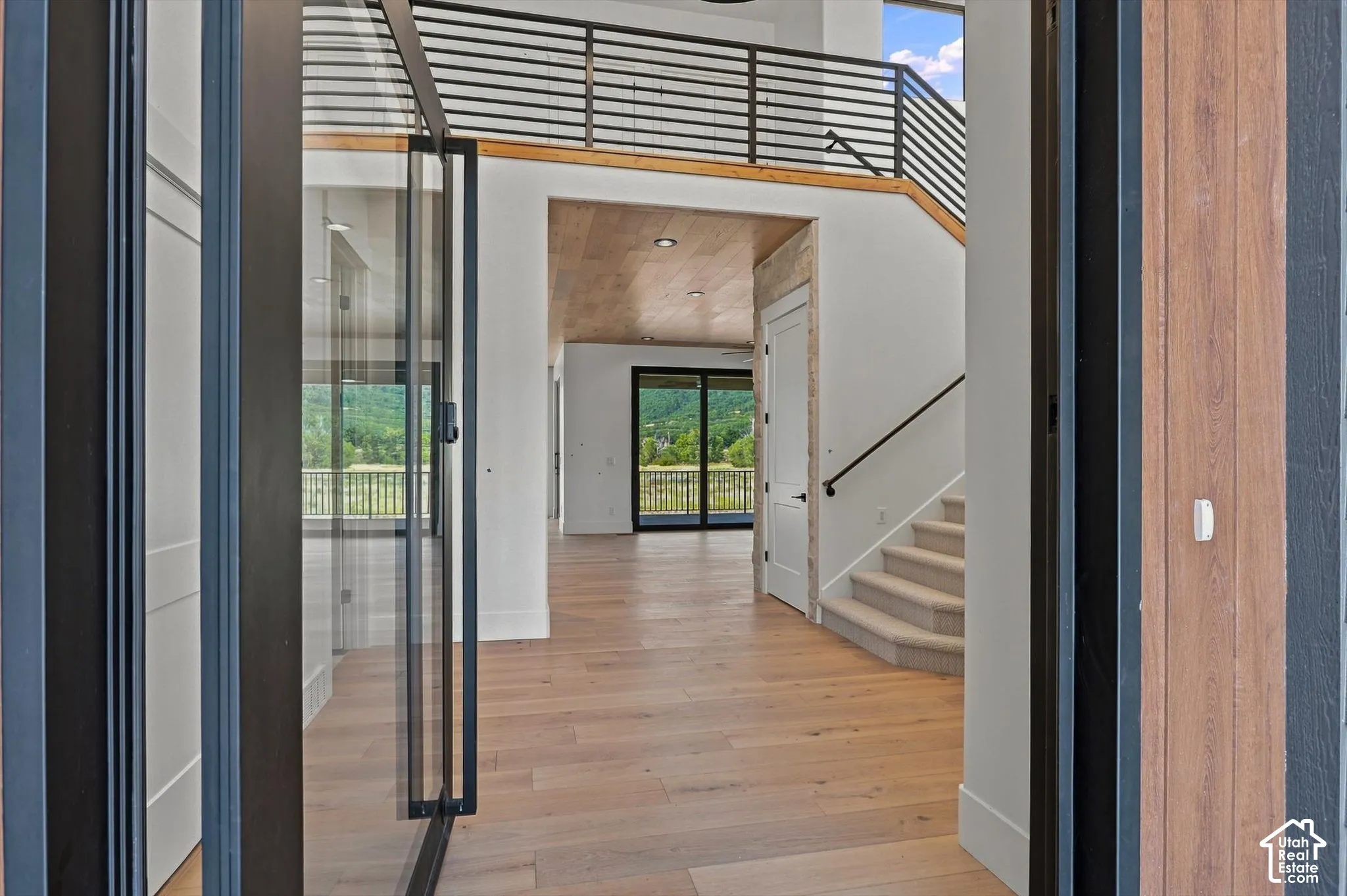 Expansive foyer with light wood-finish flooring, a two-story ceiling, and a modern open staircase with metal railings