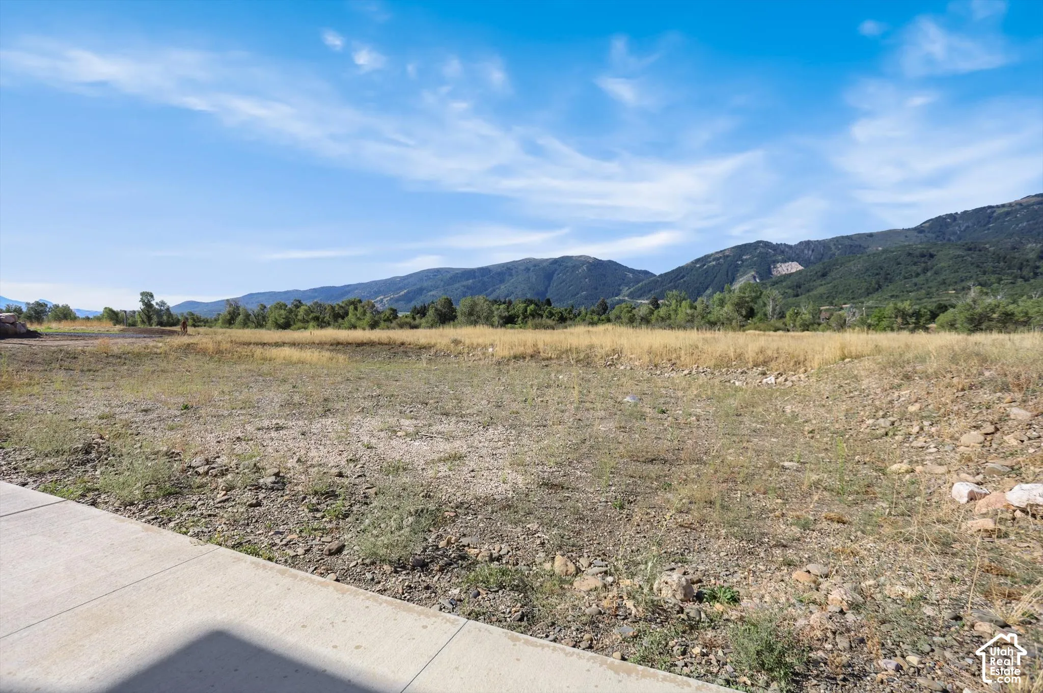 Expansive lot featuring a concrete border and a backdrop of mountainous terrain