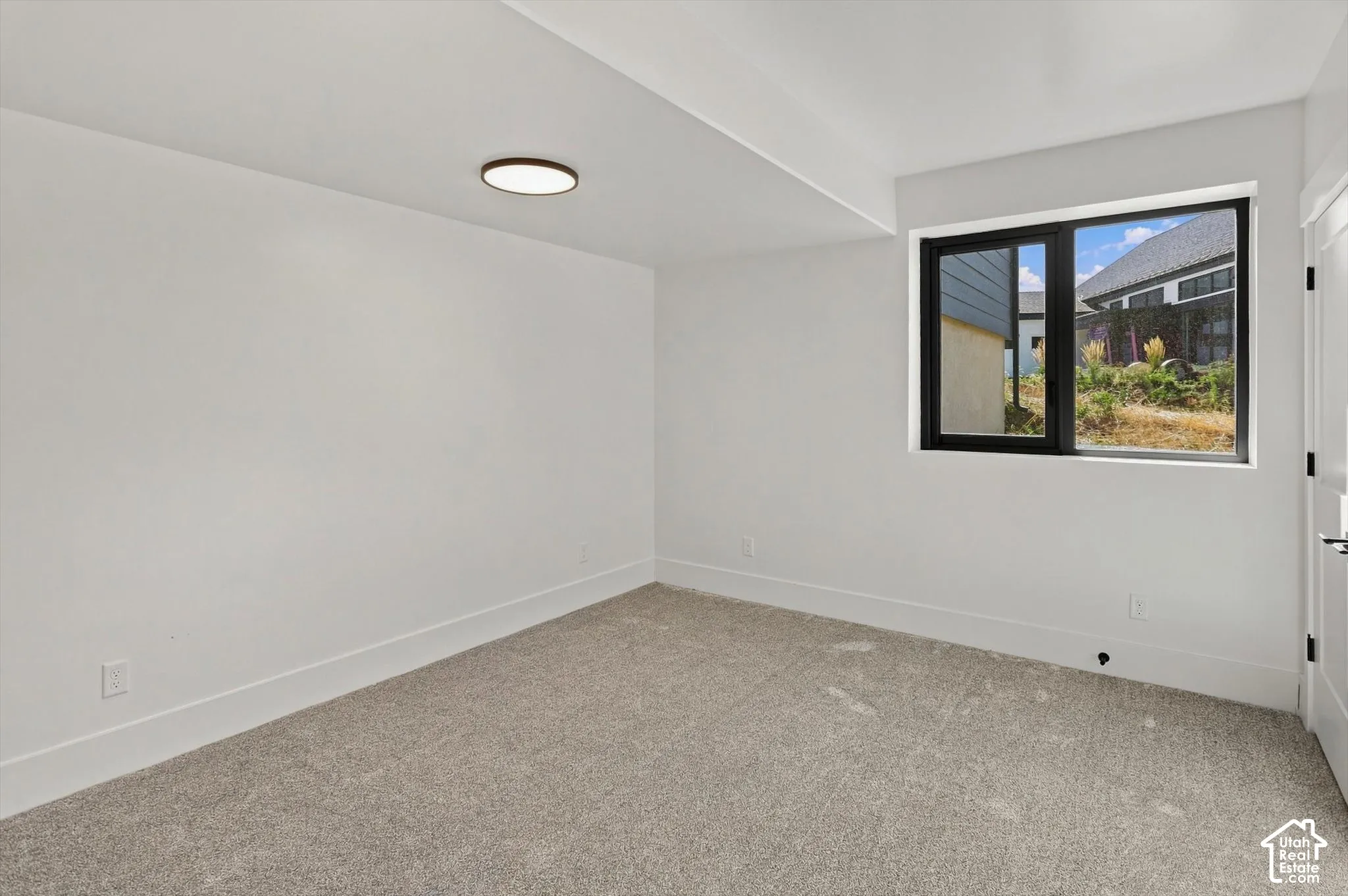 Recessed lighting, light-toned carpeting, ample natural light, bright white walls, modern black-framed window