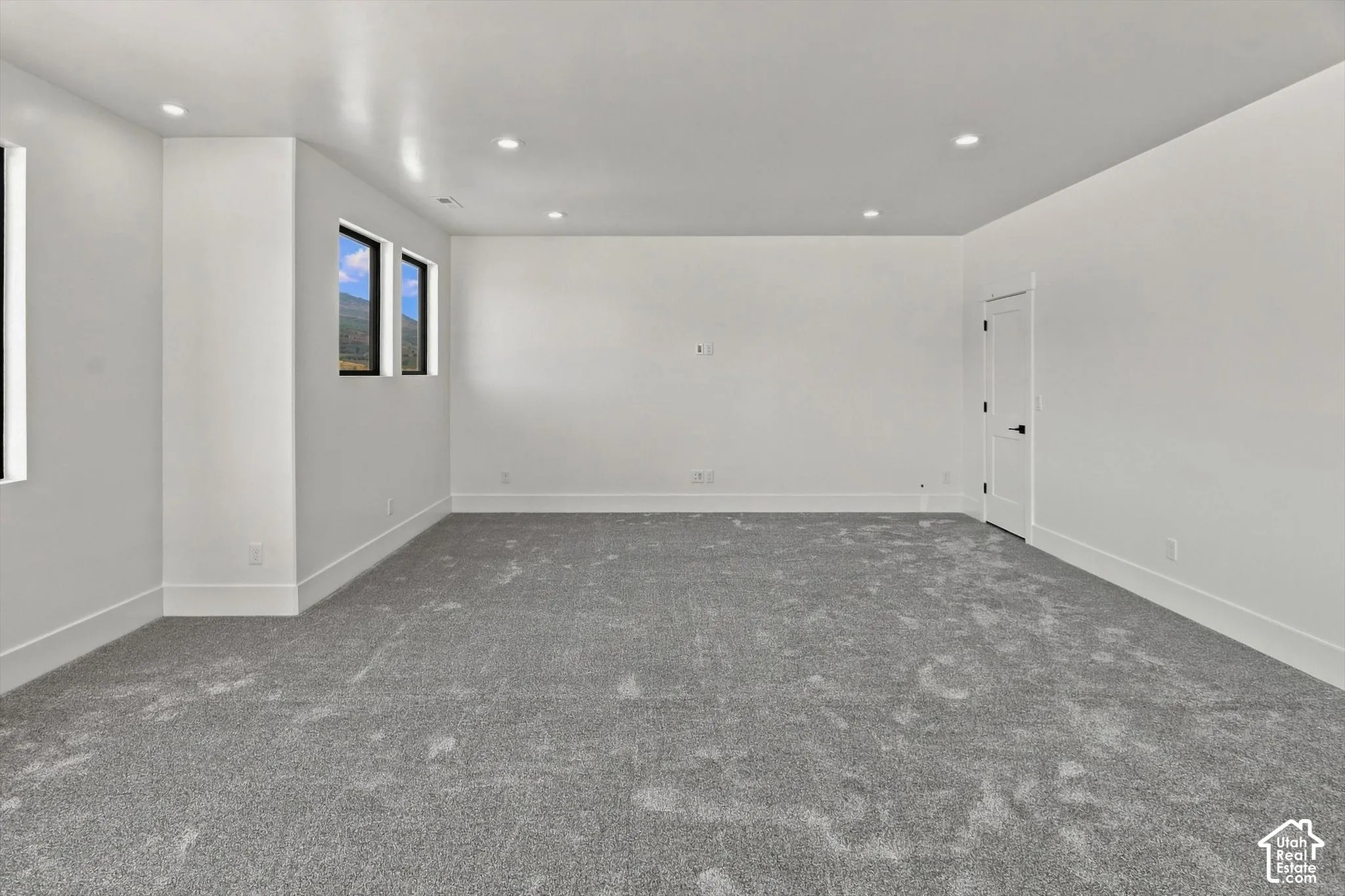 Spacious interior featuring neutral carpeting, recessed lighting, and multiple windows with mountain scenery