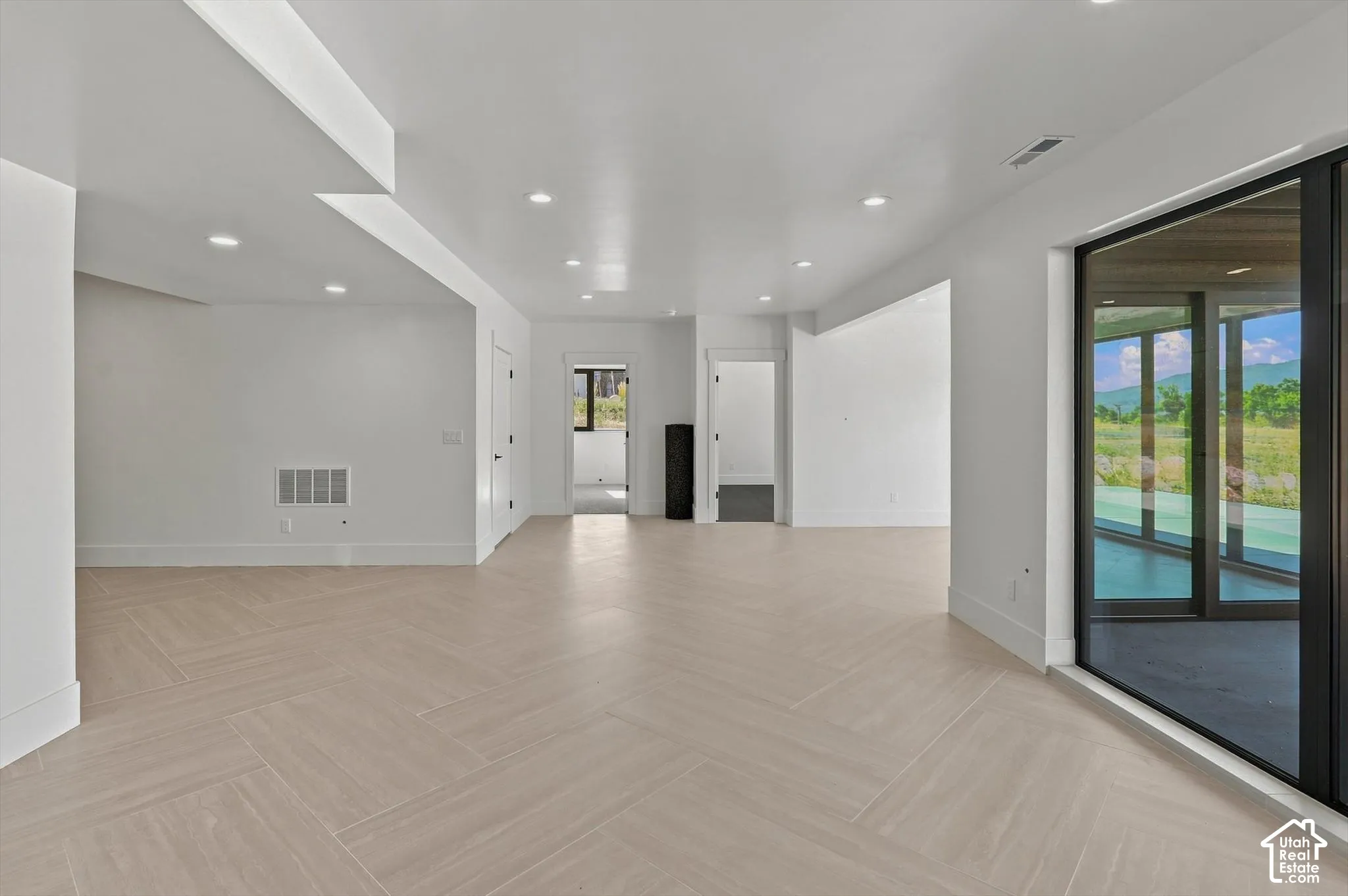 Spacious open-concept room featuring light-toned flooring in a herringbone pattern
