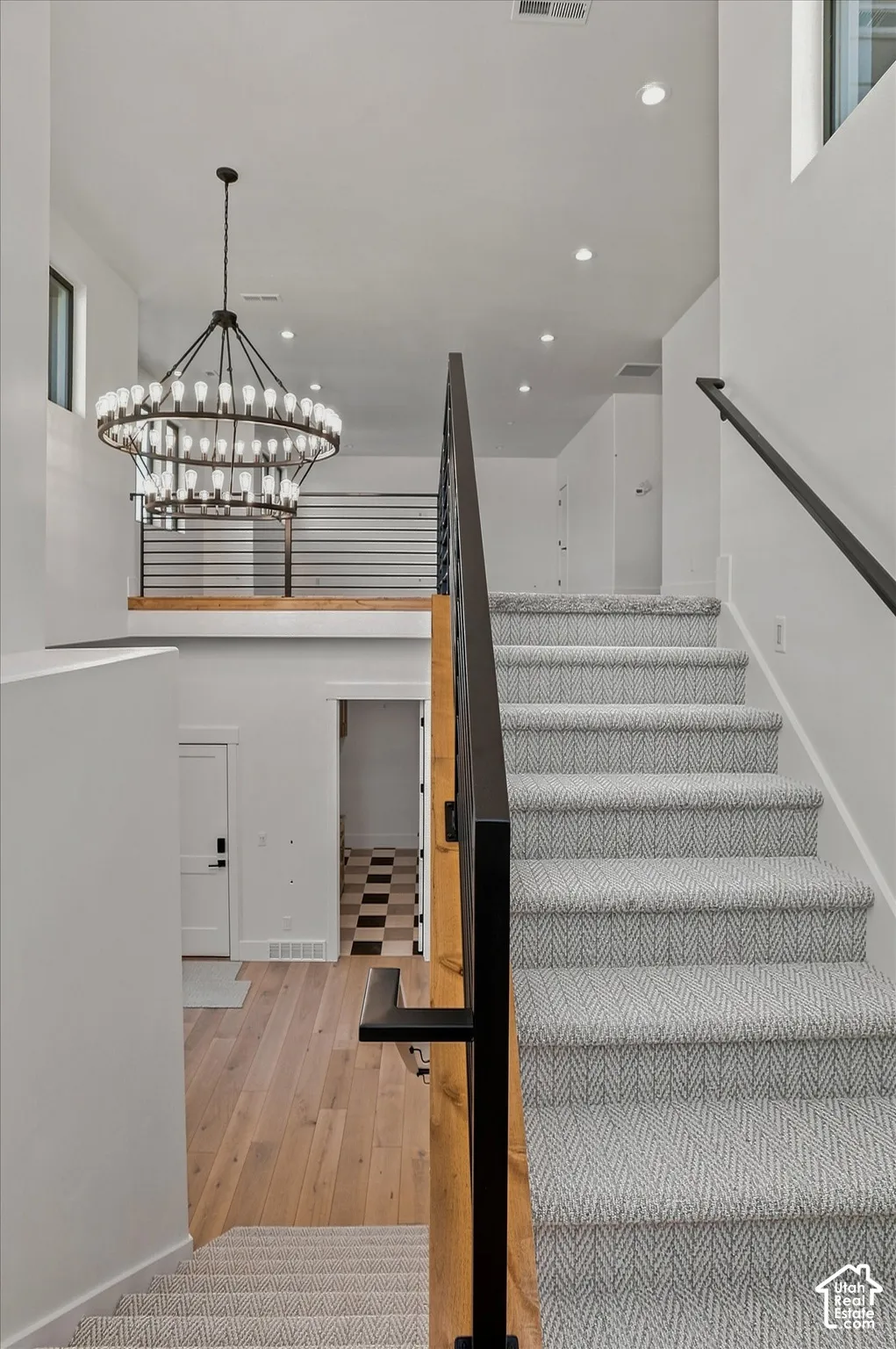 Staircase with herringbone-patterned carpet and black metal railing