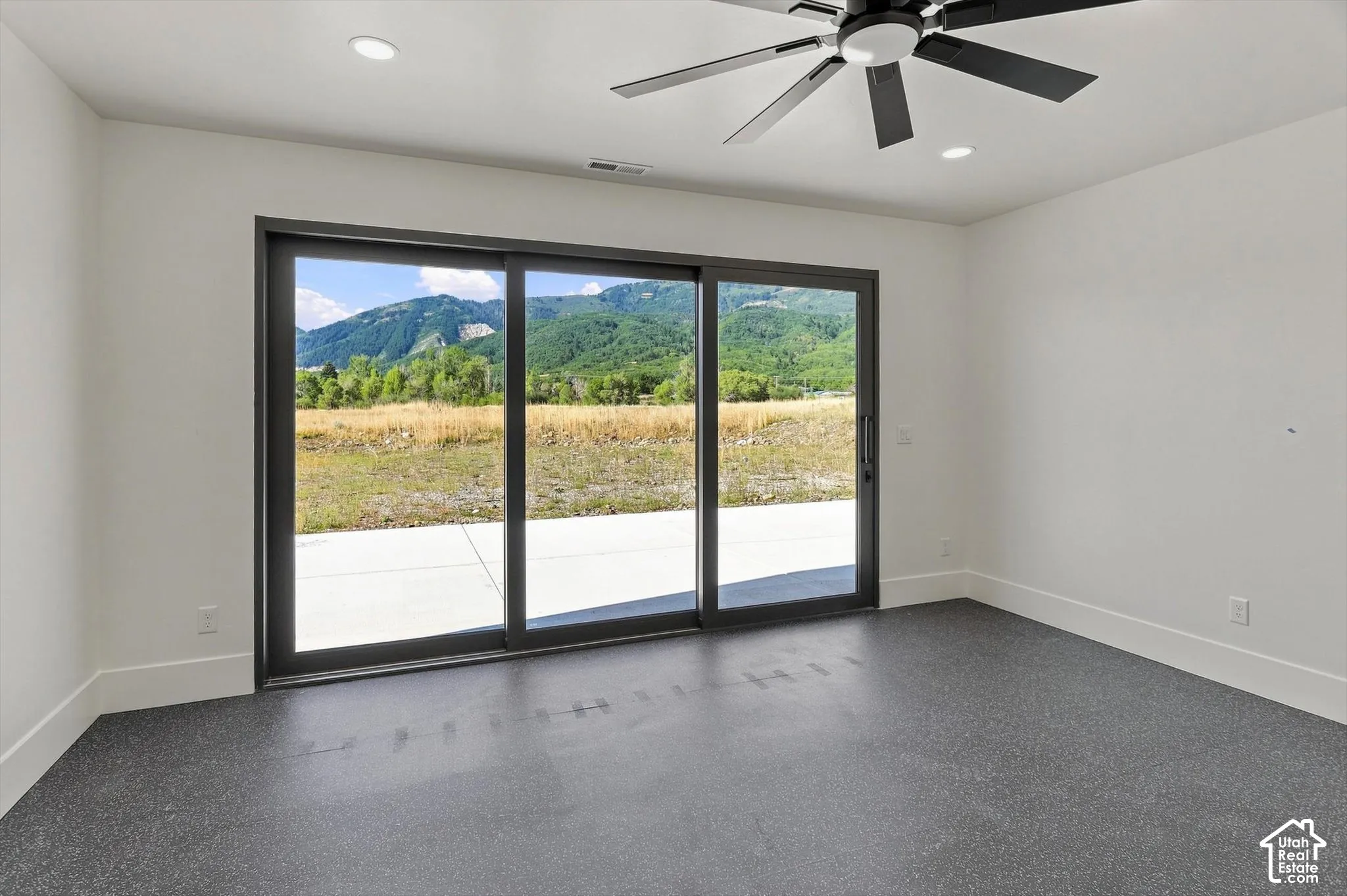 Sliding glass door, mountain scenery, overhead lighting, ceiling fan, dark speckled flooring
