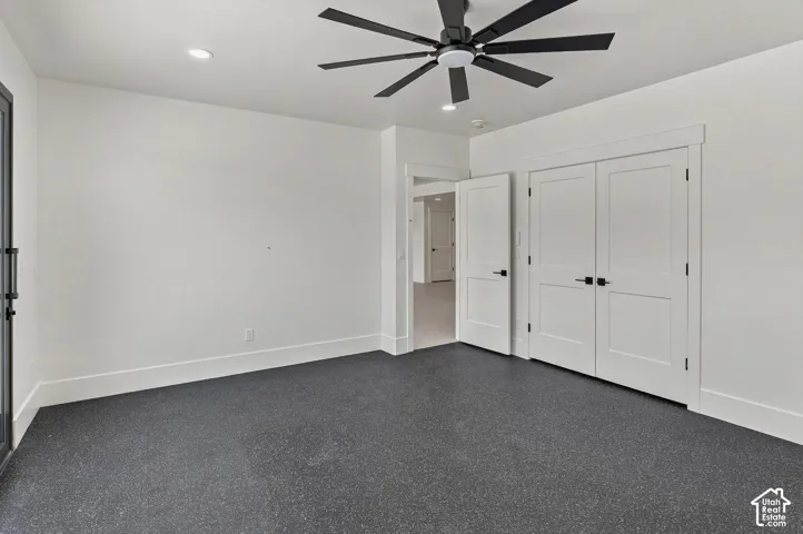 Recessed lighting, ceiling fan with black blades, white walls, dark gray flooring, and white trim