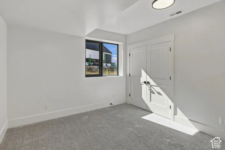 Recessed window with black trim, white interior walls, light gray carpeting, and a built-in closet with white bifold doors