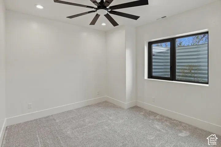 Recessed lighting, ceiling fan, white walls, gray carpet, black-framed window