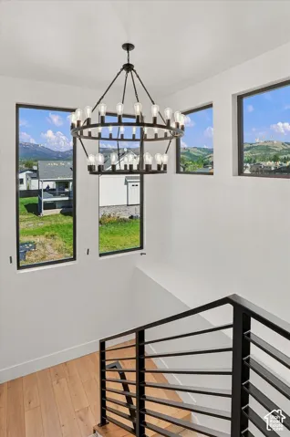 Open-concept staircase with wood-finish flooring, a modern black metal railing, and multiple windows providing natural light