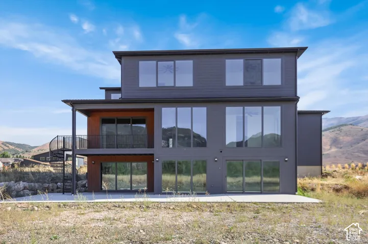 Modern multi-level exterior with extensive glazing, a spiral staircase, and a covered balcony