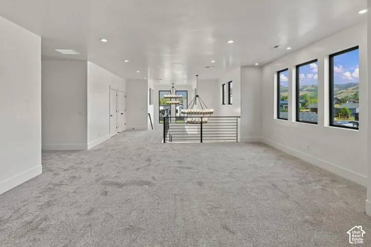Recessed lighting, three large picture windows, contemporary black metal railing, and two tiered chandeliers