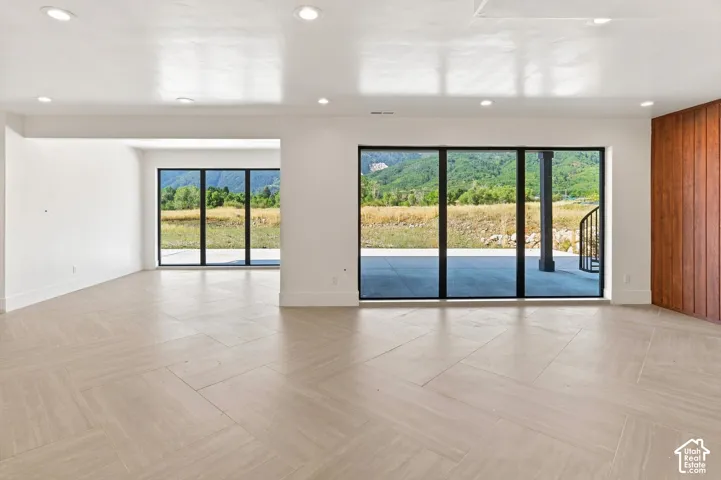 Recessed lighting, wood-finish flooring with a herringbone pattern, expansive sliding glass doors, and a wood-paneled accent wall