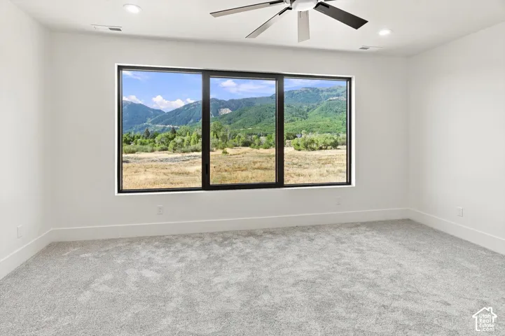 Expansive window offering mountain scenery, recessed ceiling lighting, ceiling fan, and carpeted flooring