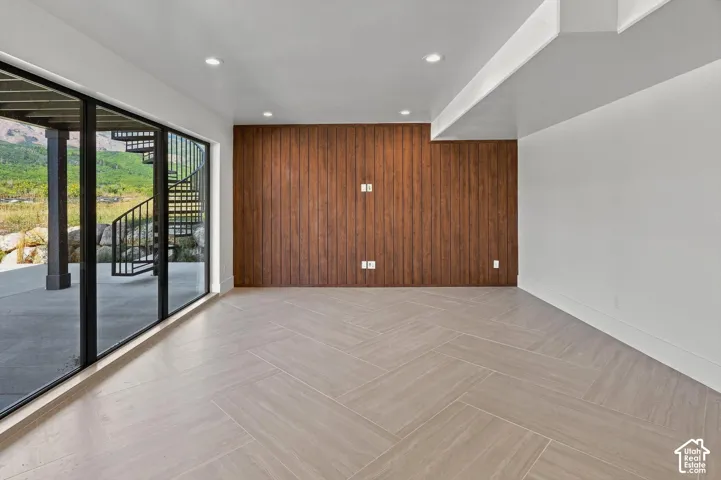 Full-height sliding glass doors, chevron-patterned tile flooring, recessed ceiling lighting, and a textured wood-panel accent wall