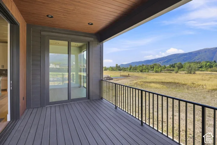 Outdoor deck featuring gray composite decking, black metal railings, and a wood-finish ceiling with recessed lighting