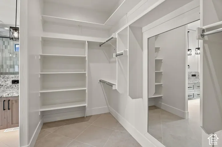 Custom built-in shelving, integrated hanging rods, full-length mirrored sliding door, light-toned floor tiling, and a neutral color palette