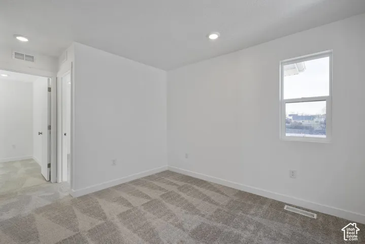 Recessed lighting, patterned carpet flooring, white baseboards, and a single window
