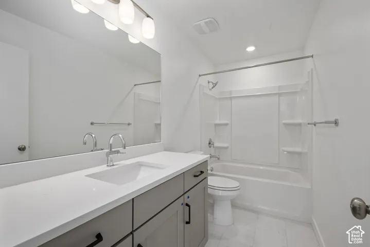 White ceramic tile flooring, a built-in vanity with gray cabinetry, a white countertop, and a vanity mirror with overhead lighting