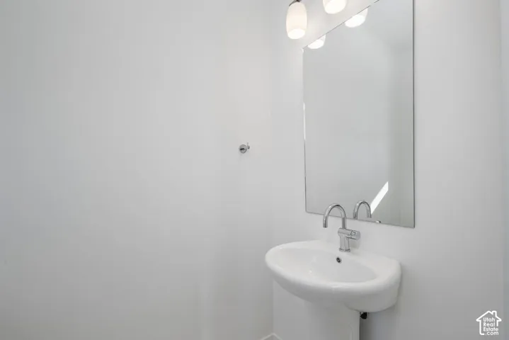 Pedestal sink with chrome faucet, frameless mirror, and integrated vanity lighting