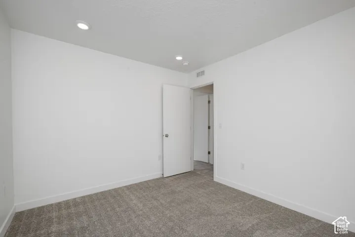 Neutral wall paint, recessed ceiling lighting, and gray carpet flooring
