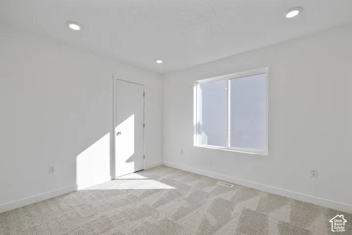 Recessed ceiling lighting, white walls, white trim, carpeted flooring, and a single window