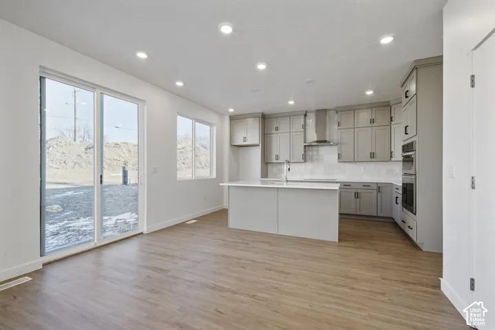 Kitchen featuring wood-finish flooring, recessed lighting, and a center island with an undermount sink