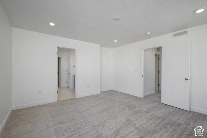Recessed ceiling lighting, white walls, light gray carpeting, and white trim