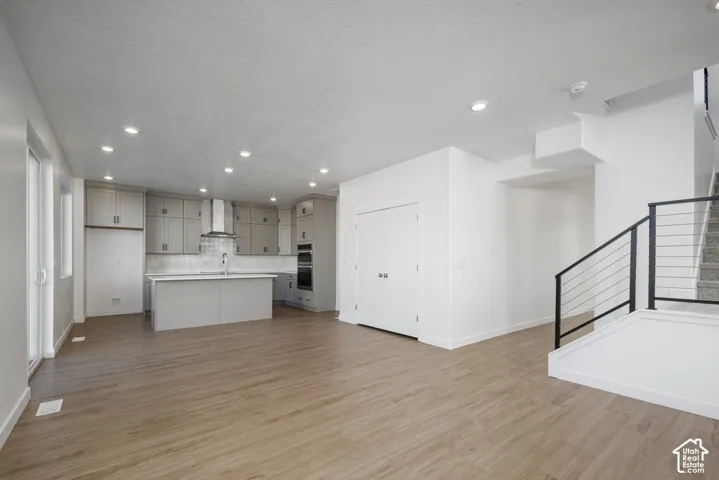 Open-concept living space with wood-finish flooring, recessed lighting, and a modern kitchen