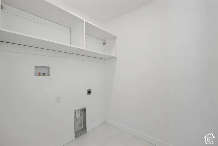 Utility area featuring built-in shelving, plumbing hookups, electrical outlet, and ventilation