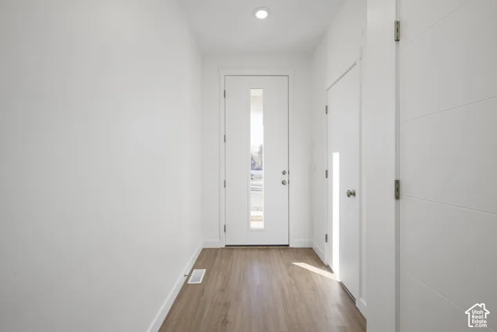 White interior walls, recessed ceiling lighting, wood-finish flooring, and white interior doors with contemporary hardware