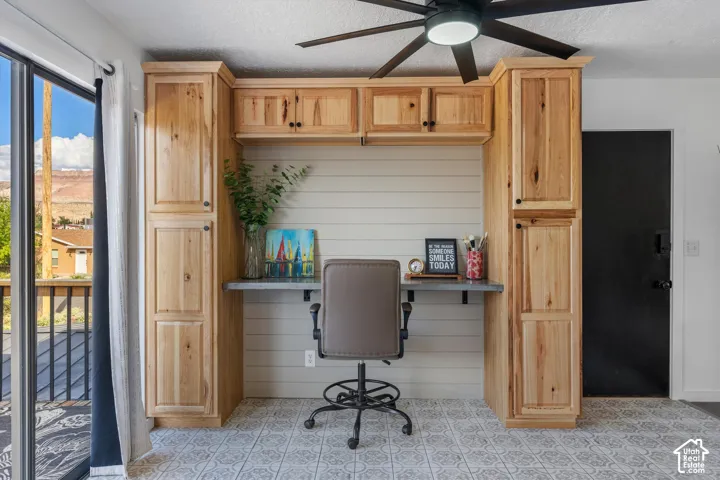 Built-in cabinetry with ample storage, a dedicated desk area, and a ceiling fan