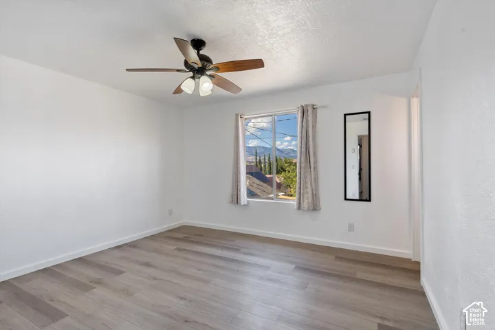 Wood-finish flooring, ceiling fan with integrated lighting, and white walls
