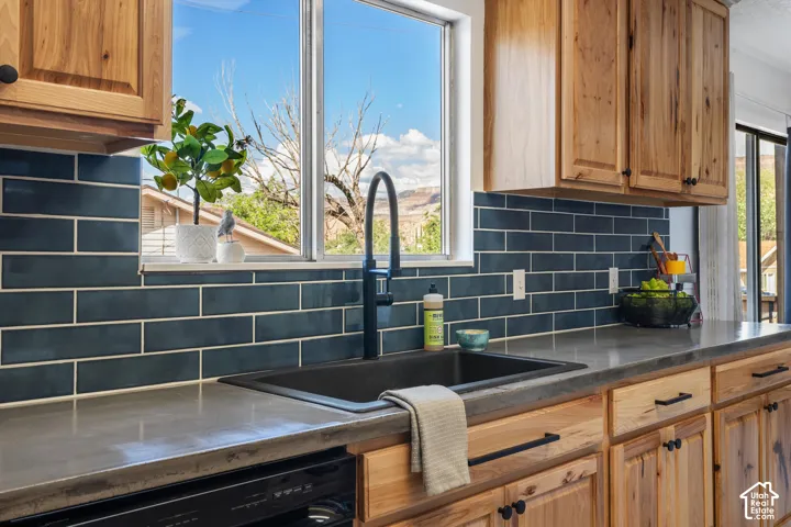 Concrete-finish countertops, wood cabinetry, a black single-basin sink, and a black gooseneck faucet