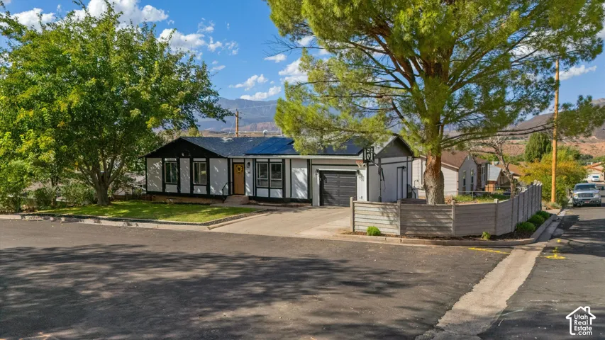 Contemporary exterior with dark trim and light siding, attached garage, solar panels, and a paved driveway